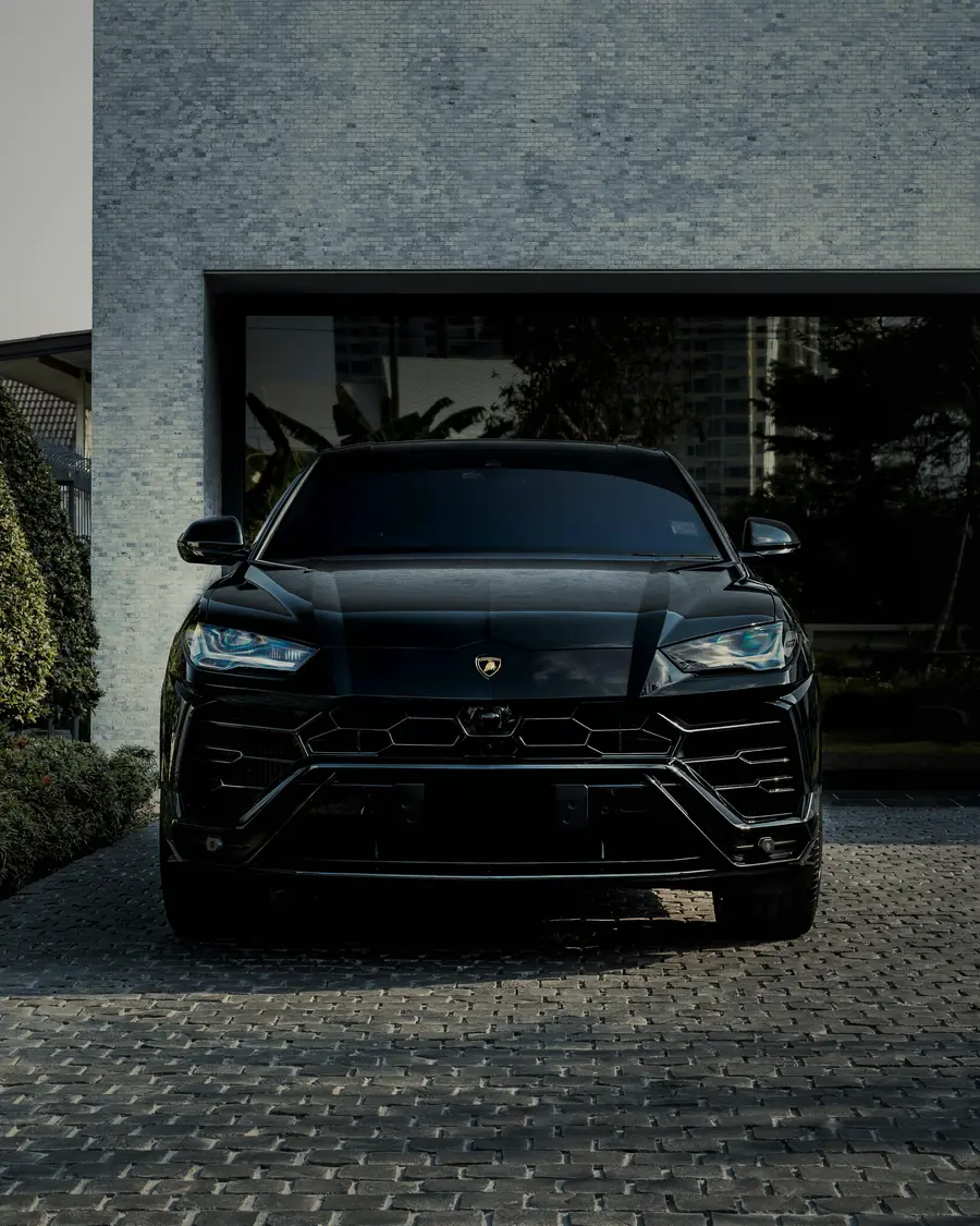 Lamborghini Urus at an entrance under palms, black